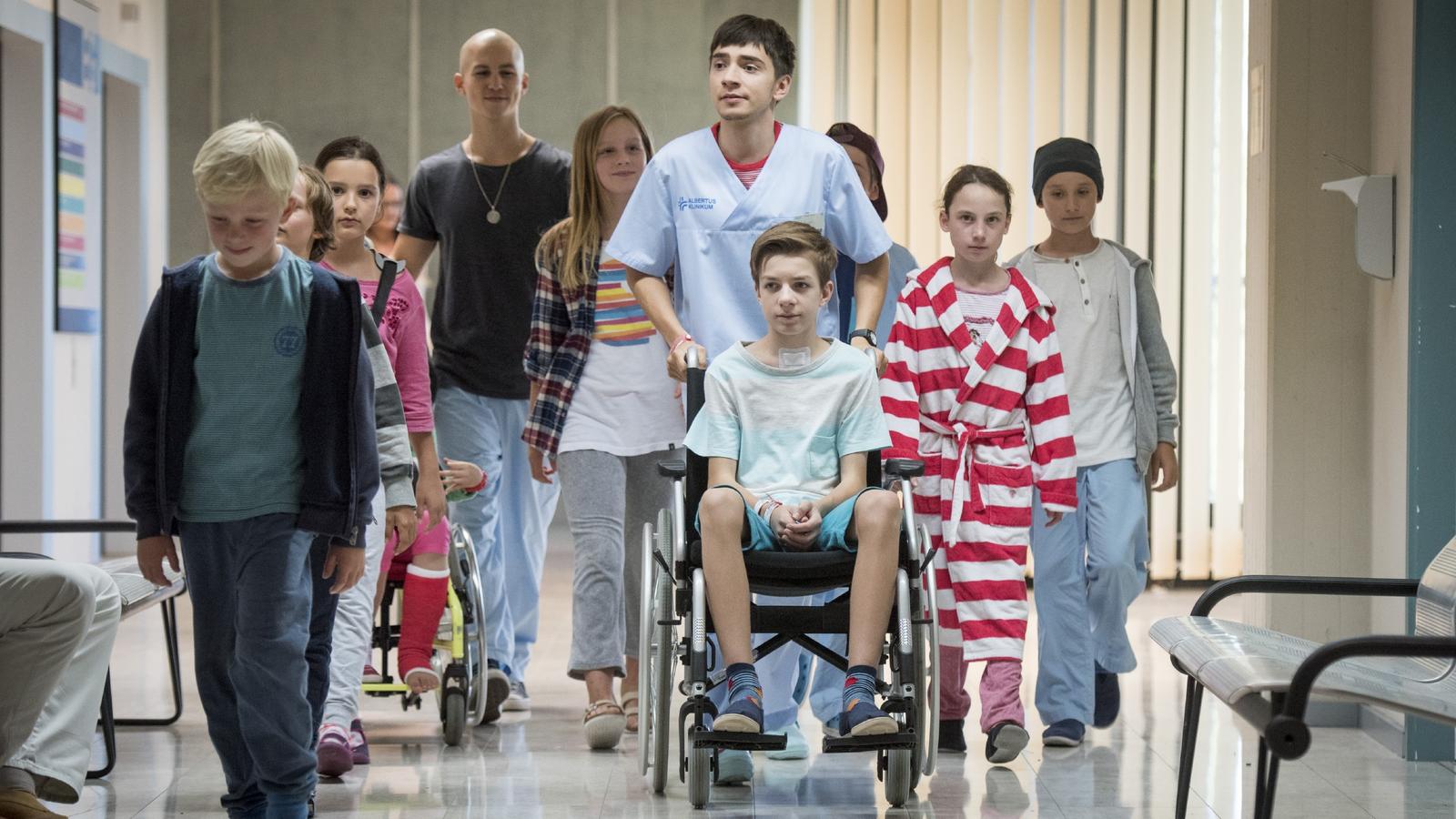 Club der roten Bänder: Hugo will die kleine Patientin Sara zurück ins Leben singen V.l.: Leo (Tim Oliver Schultz), Toni (Ivo Kortlang) und Hugo (Nick Julius Schuck) werden von den Kindern der Kinderstation begleitet, ein Mädchen zu besuchen, das im Koma liegt.